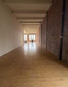 A long empty gallery, brick and daylight, a figure at the far end