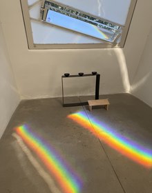 A prism on its stand, laying a rainbow across the floor
