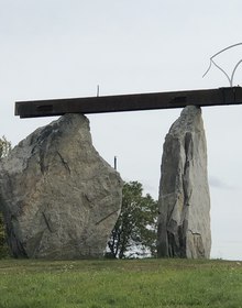 A rusted girder laid across two standing stones