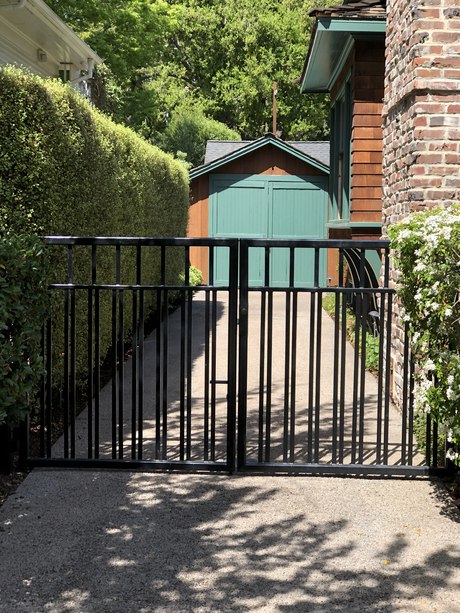 Green garage doors at the end of the drive, seen through the gate