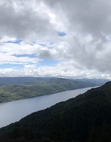 Loch Ness running south between forested hills under broken cloud