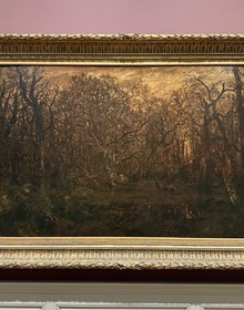 Gilt-framed forest painting on a rose gallery wall